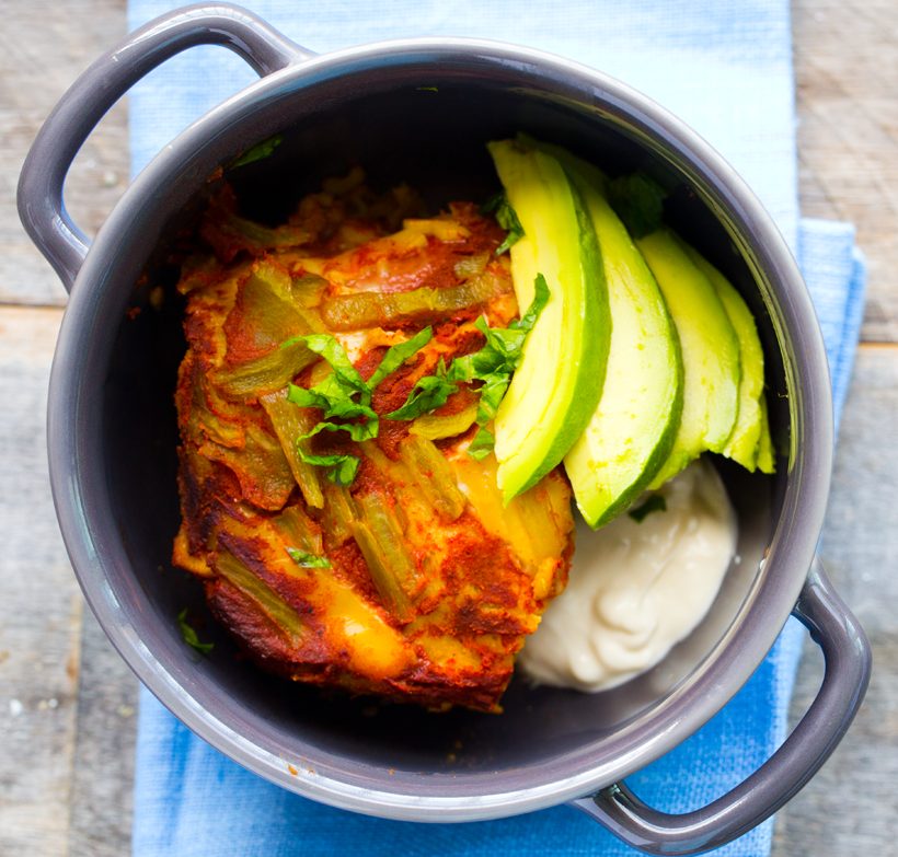 Vegan enchilada casserole with layers of corn tortillas, beans, red rice, spinach, hatch chiles and vegan cheese.