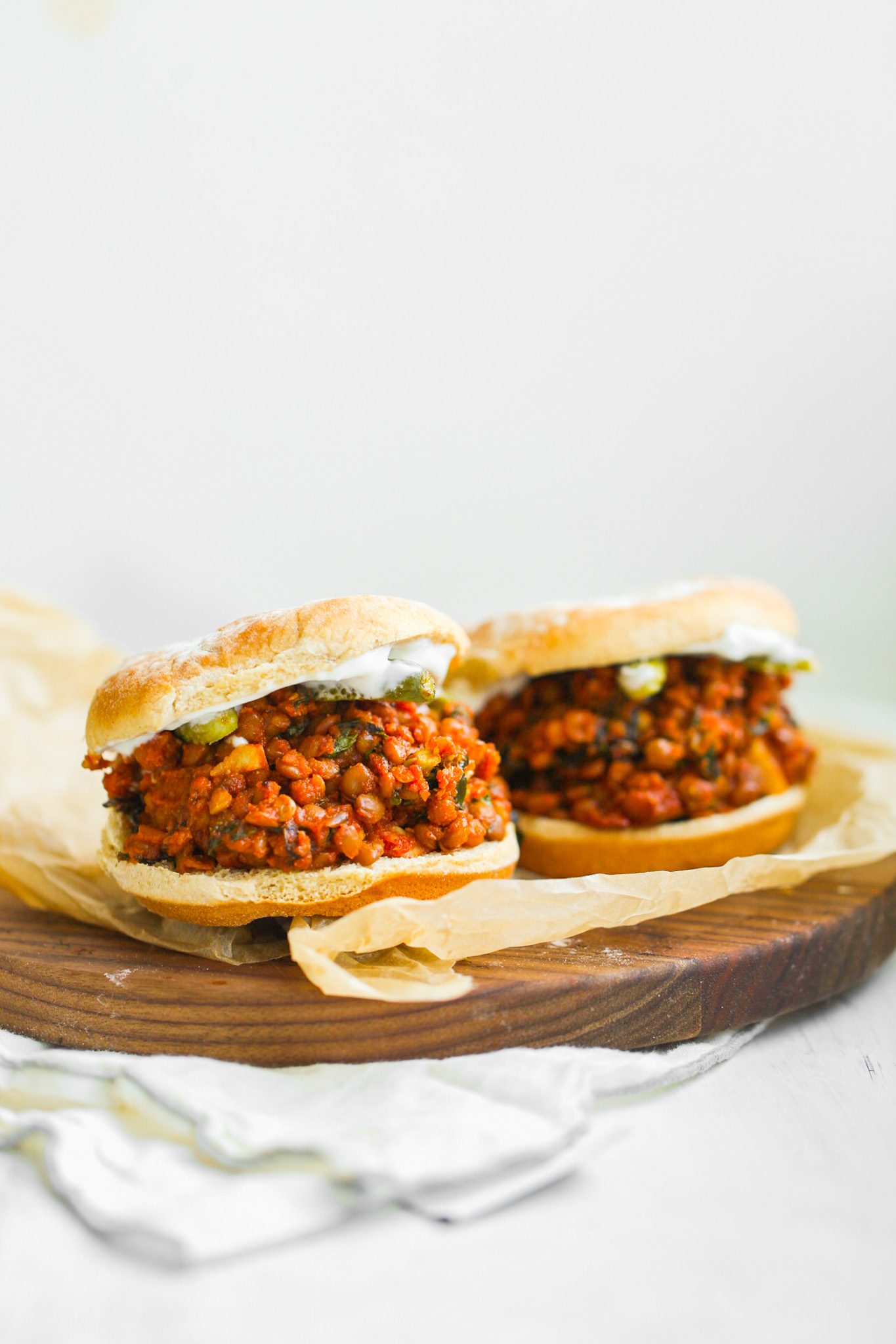 Vegan sloppy joes with lentils in a rich tomato sauce, served on toasted buns with sliced pickles.