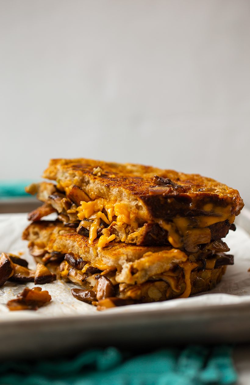 A grilled cheese sandwich with melted vegan cheddar and smoky shiitake mushroom bacon on toasted sourdough bread.