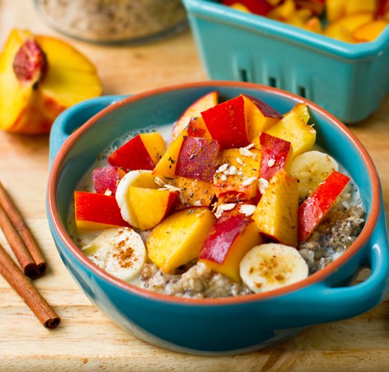 Warm oatmeal topped with peaches, nectarines, banana slices and chia seeds, drizzled with maple syrup and surrounded by creamy soy milk.