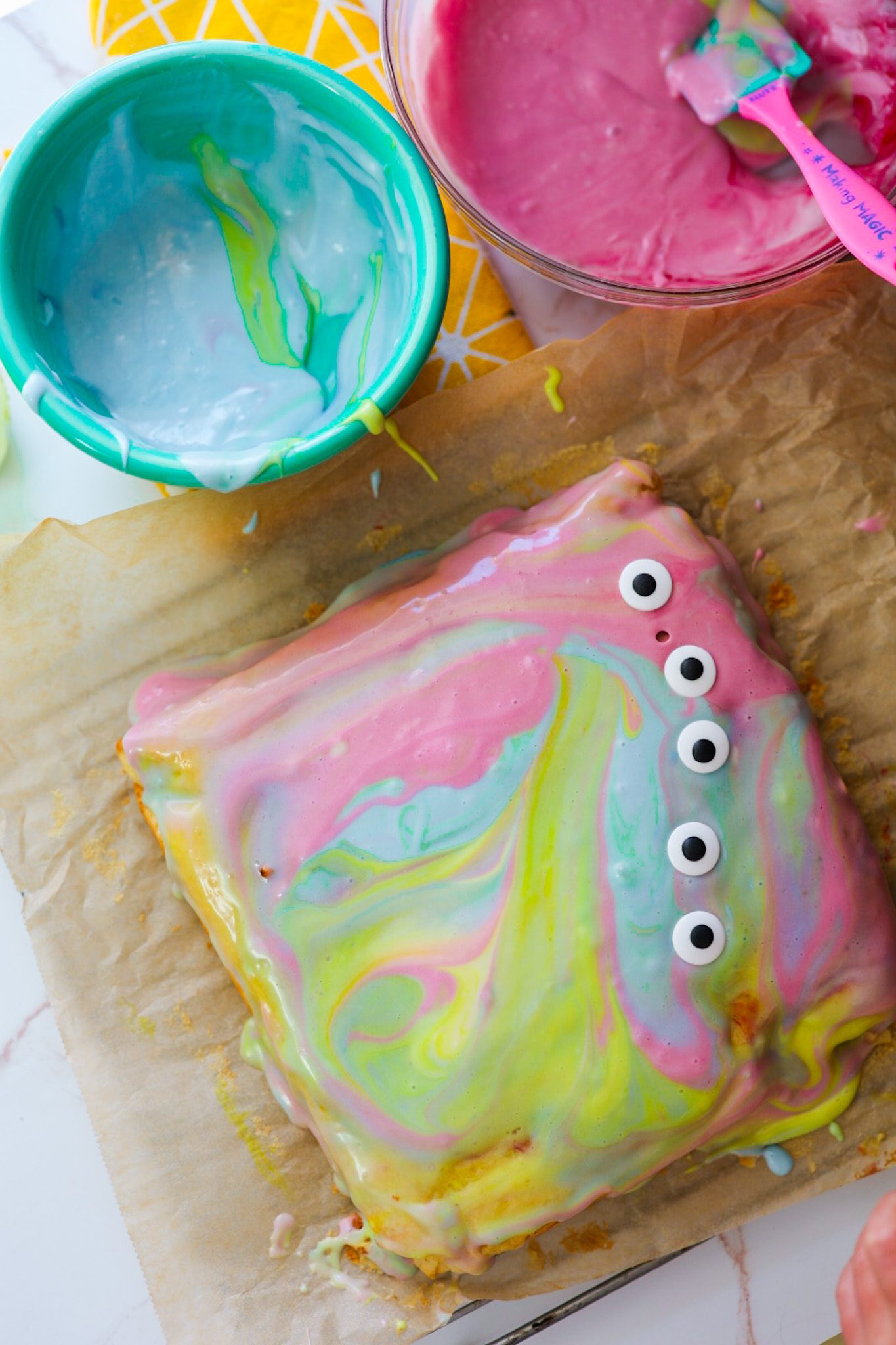 Lemon cake swirled with bright colors, topped with colorful vegan cream cheese frosting and candy eyeballs.