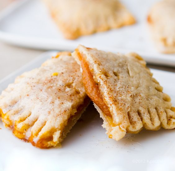 Heart-shaped and rectangular pumpkin pie tarts with flaky cinnamon crusts, crimped edges, and a drizzle of vanilla glaze.