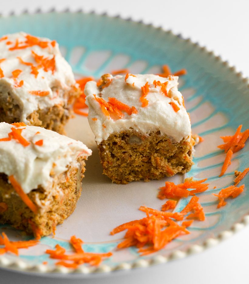 Vegan carrot cake studded with walnuts and carrot shreds, topped with fluffy coconut cream cheese frosting.