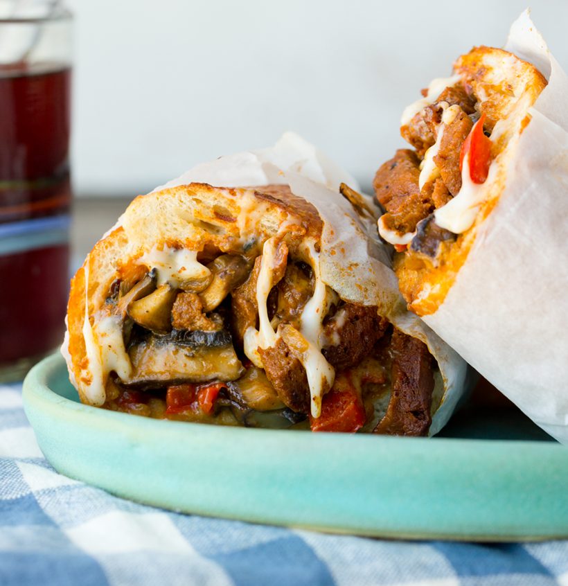 Vegan Philly cheese sandwich filled with mushrooms and melted dairy-free cheese on a sourdough roll.