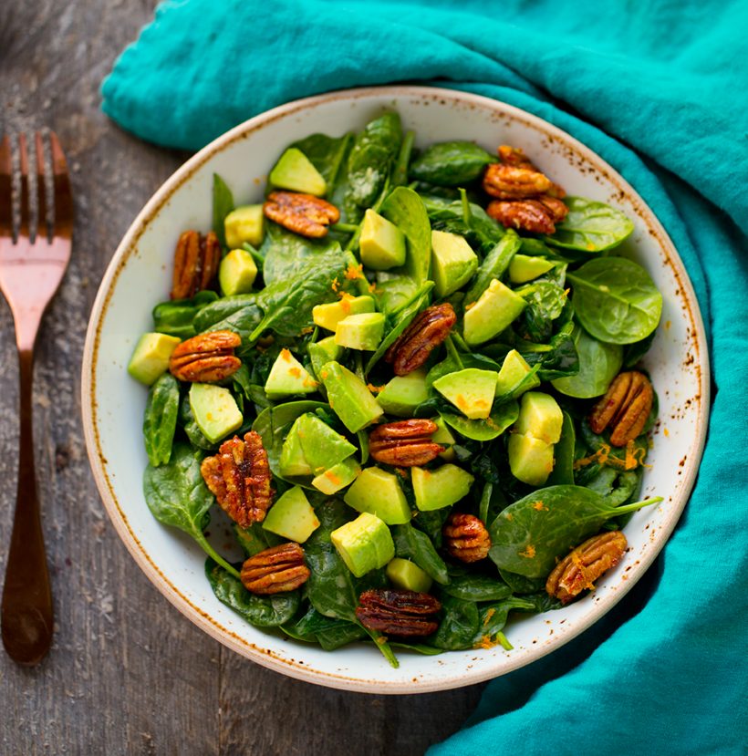 Spinach salad with sweet candied pecans, buttery avocado, maple-mustard dressing, orange zest and black pepper.