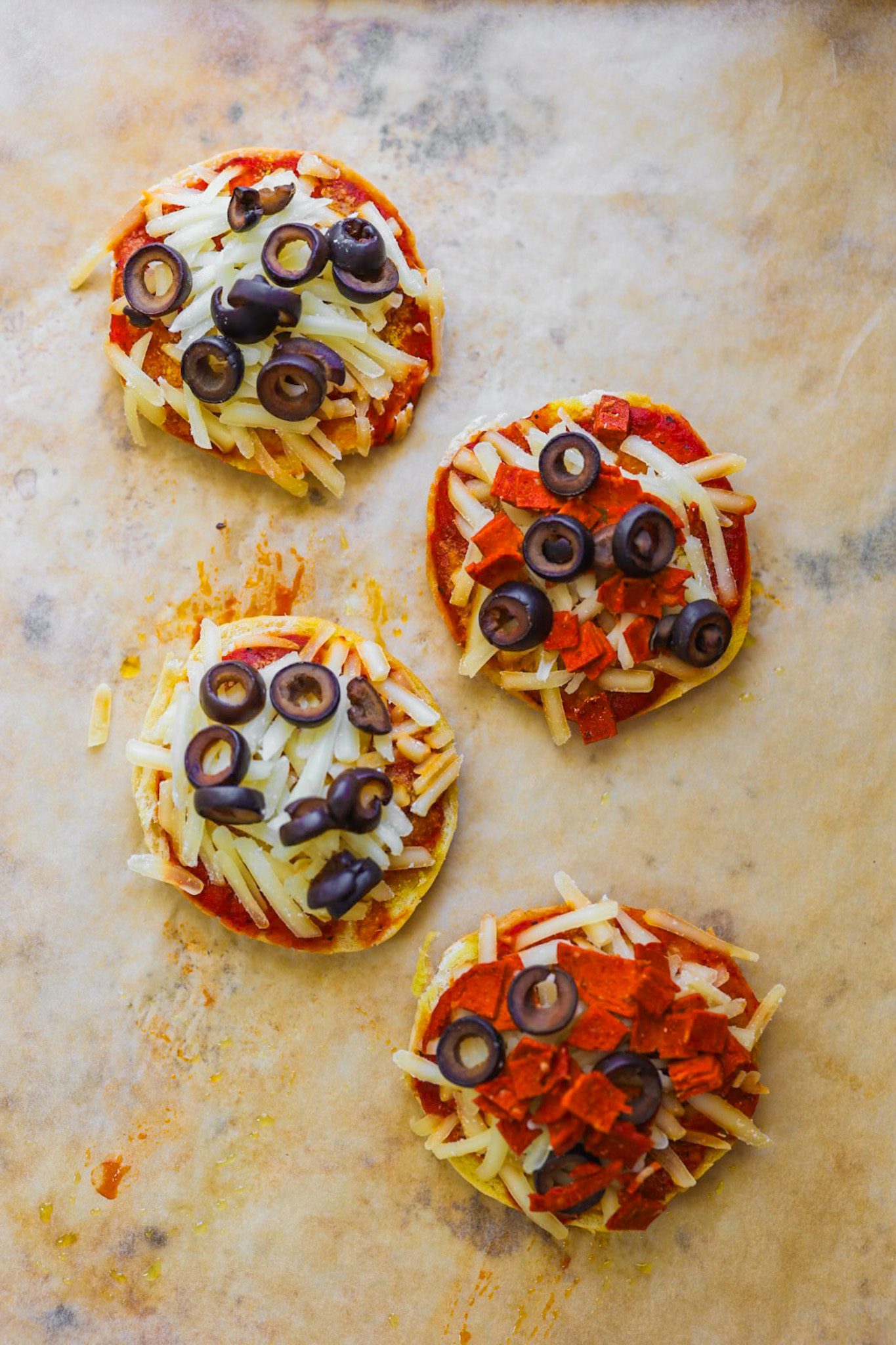 Mini English muffin pizzas topped with tomato sauce, melted vegan cheese, and small cubes of vegan pepperoni.