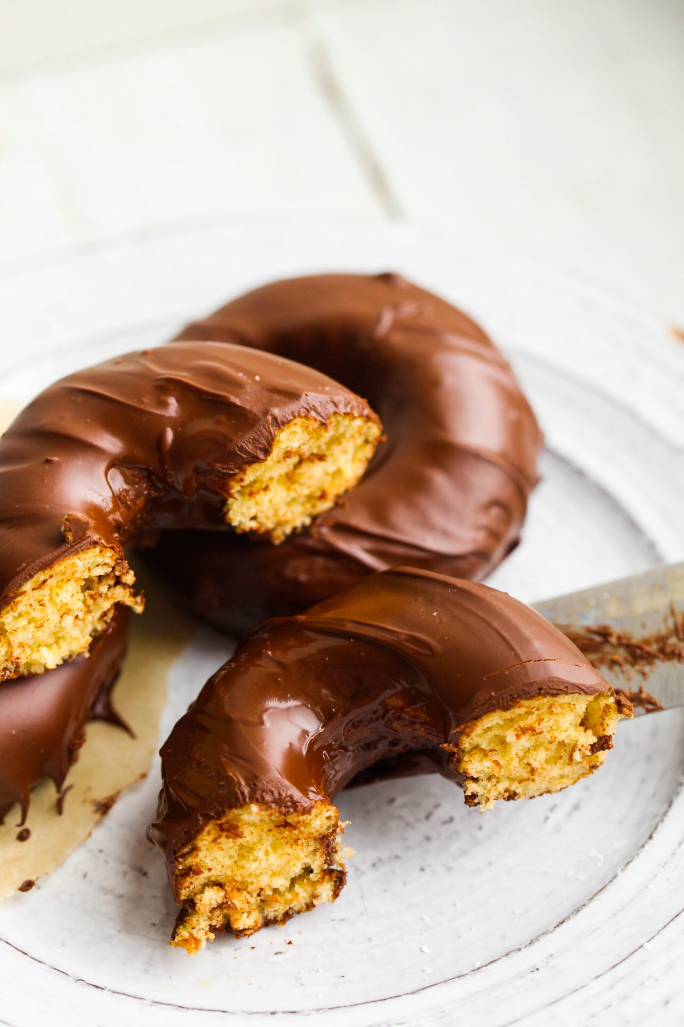 Sliced baked vanilla donuts coated in rich chocolate, revealing their fluffy interiors.