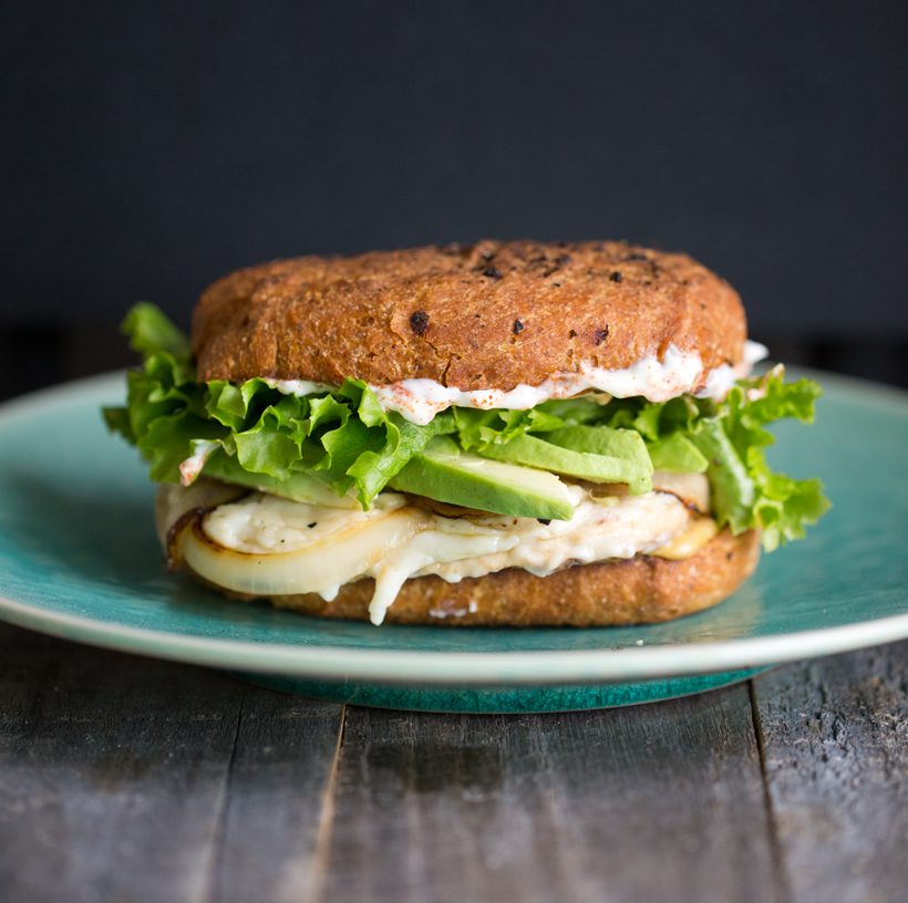 Vegan chickn sandwich with melted vegan cheese, avocado, lettuce, caramelized onions, Dijon mustard and smoky vegan mayo.