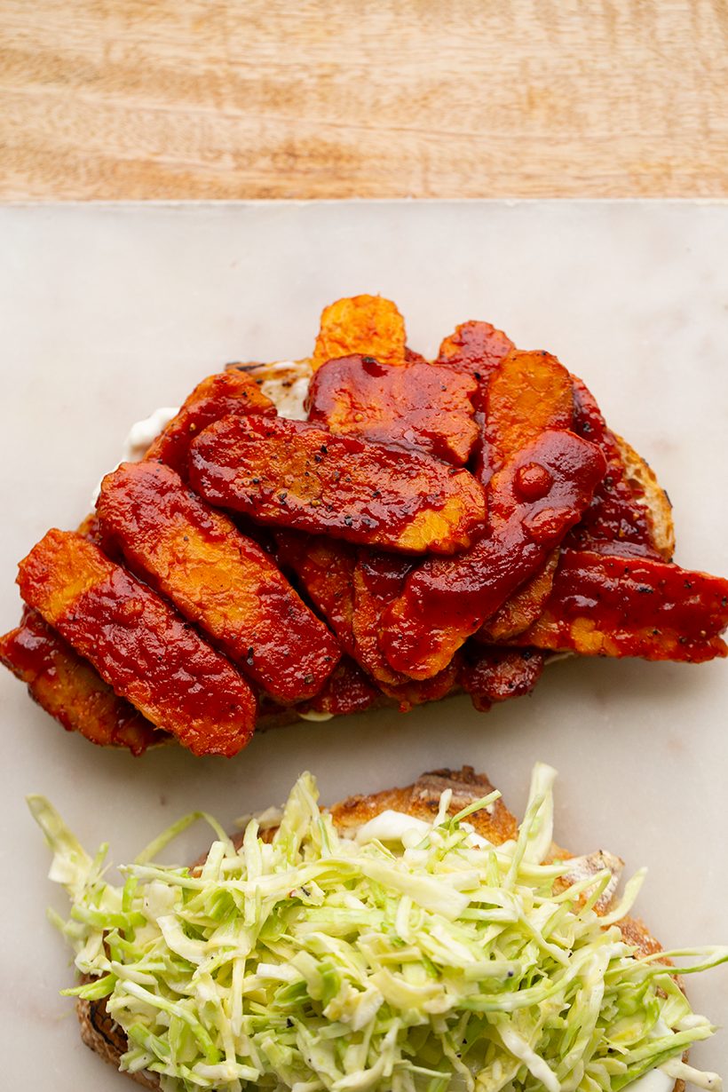 A hearty sandwich stacked with barbecue-coated tempeh and crunchy, creamy cabbage slaw.