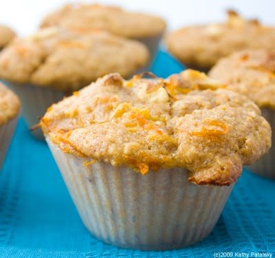 Soft orange-colored muffins with citrus, spicy ginger and walnuts, topped with orange zest, walnut bits and raw sugar.