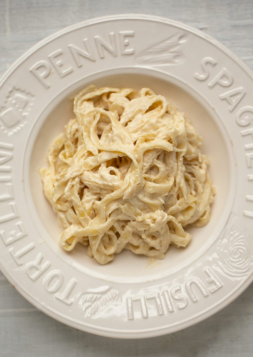 Tender fettuccine coated in a velvety, cashew-based vegan Alfredo sauce and garnished with chopped herbs.