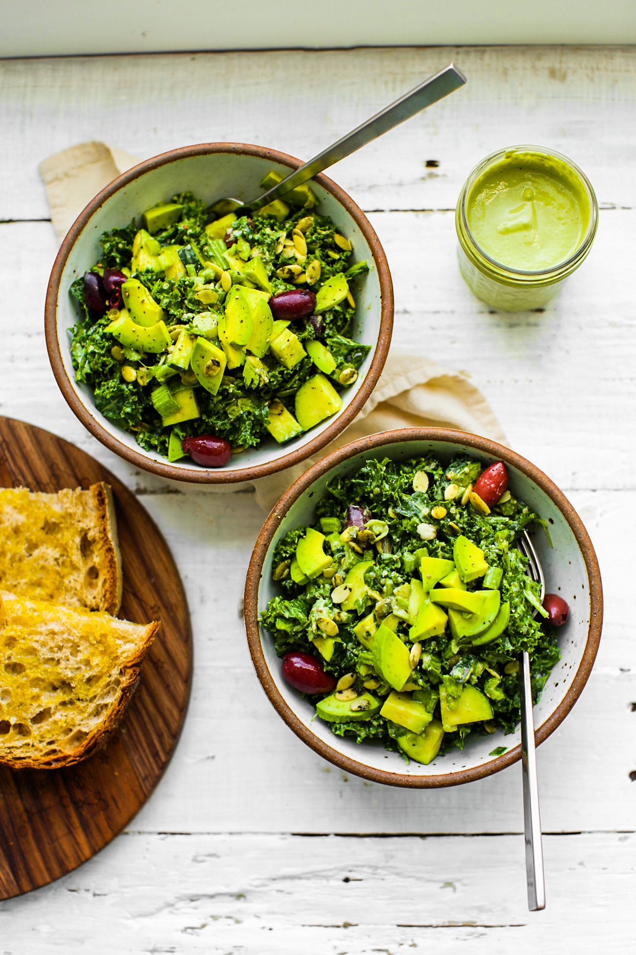 Curly kale salad with avocado, kalamata olives, cucumber, green pepper, hemp seeds and pumpkin seeds tossed in green goddess dressing.