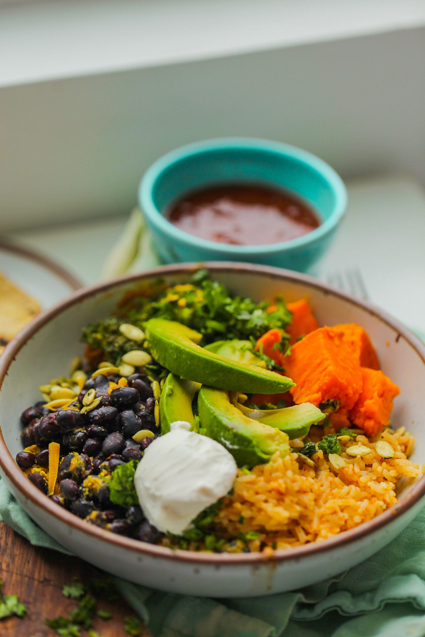 Vegan burrito bowl with seasoned rice, black beans, sweet potato, avocado, cilantro and salsa.