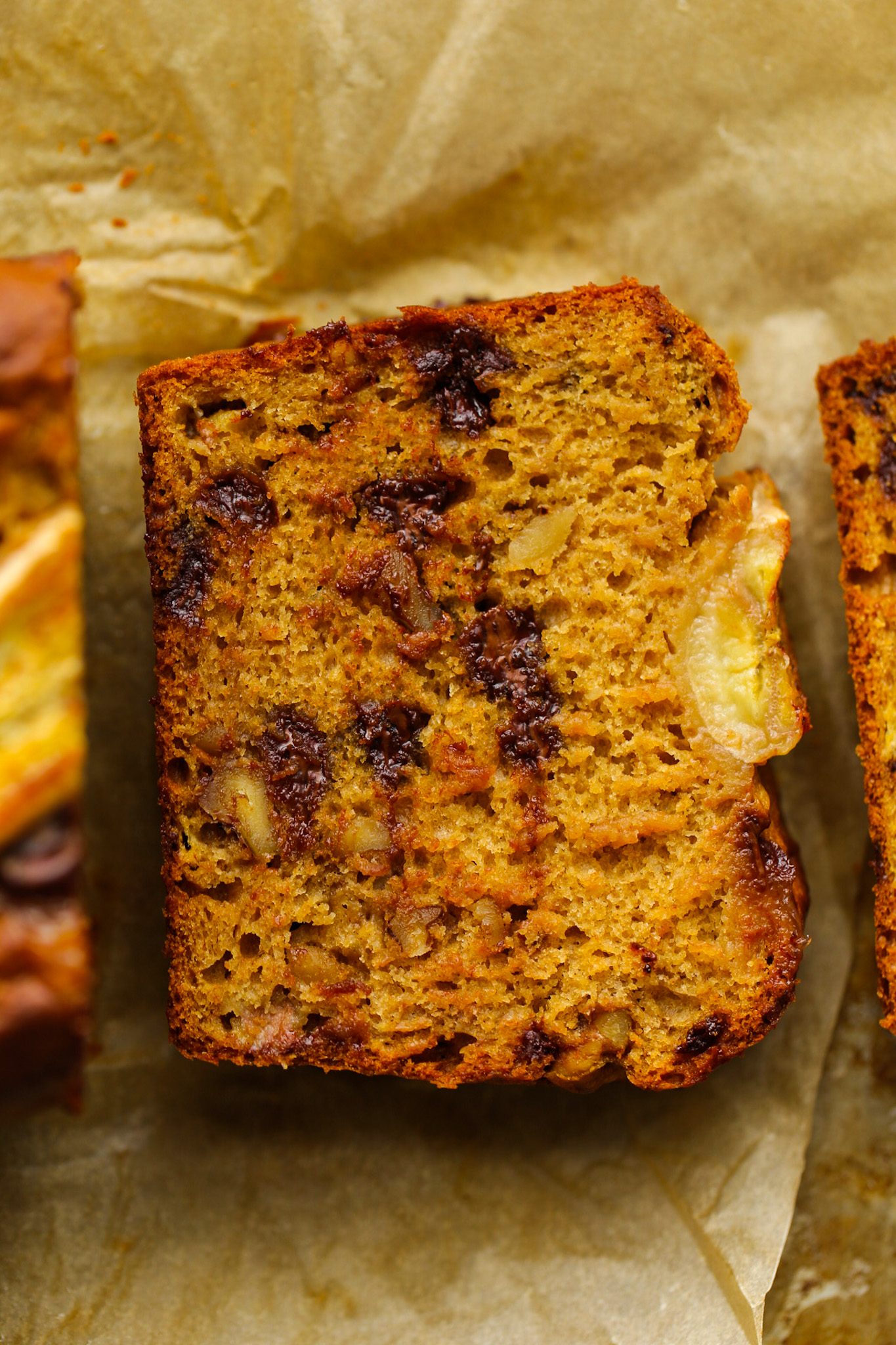 Fluffy banana bread filled with chocolate chips and chunky walnuts, topped with a thick slice of baked banana.