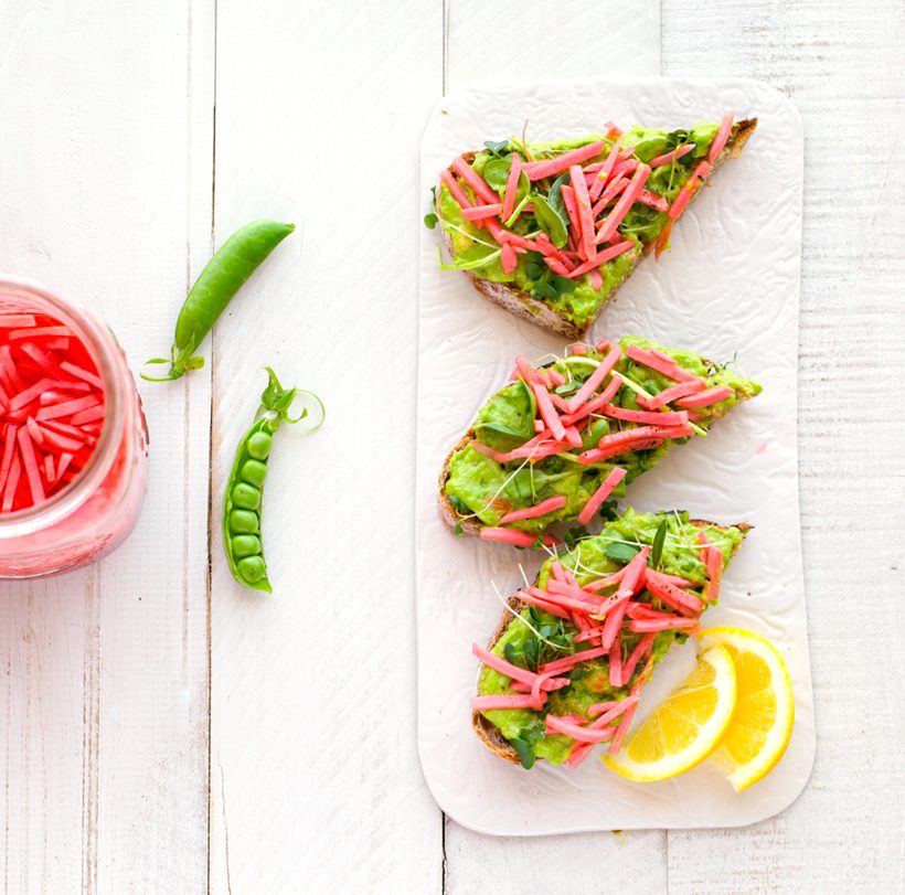 Crusty toast topped with chunky avocado and spring pea spread, pickled radishes, and fresh sprouts.