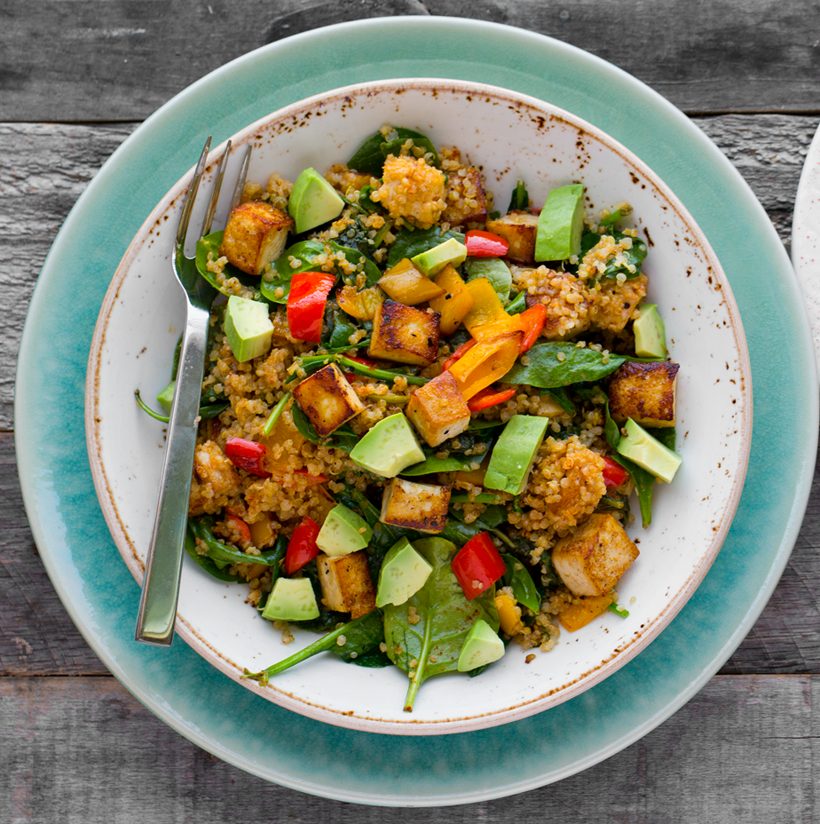 Spicy tofu and quinoa bowl with spinach, bell pepper, diced avocado, and Medjool date lime dressing.