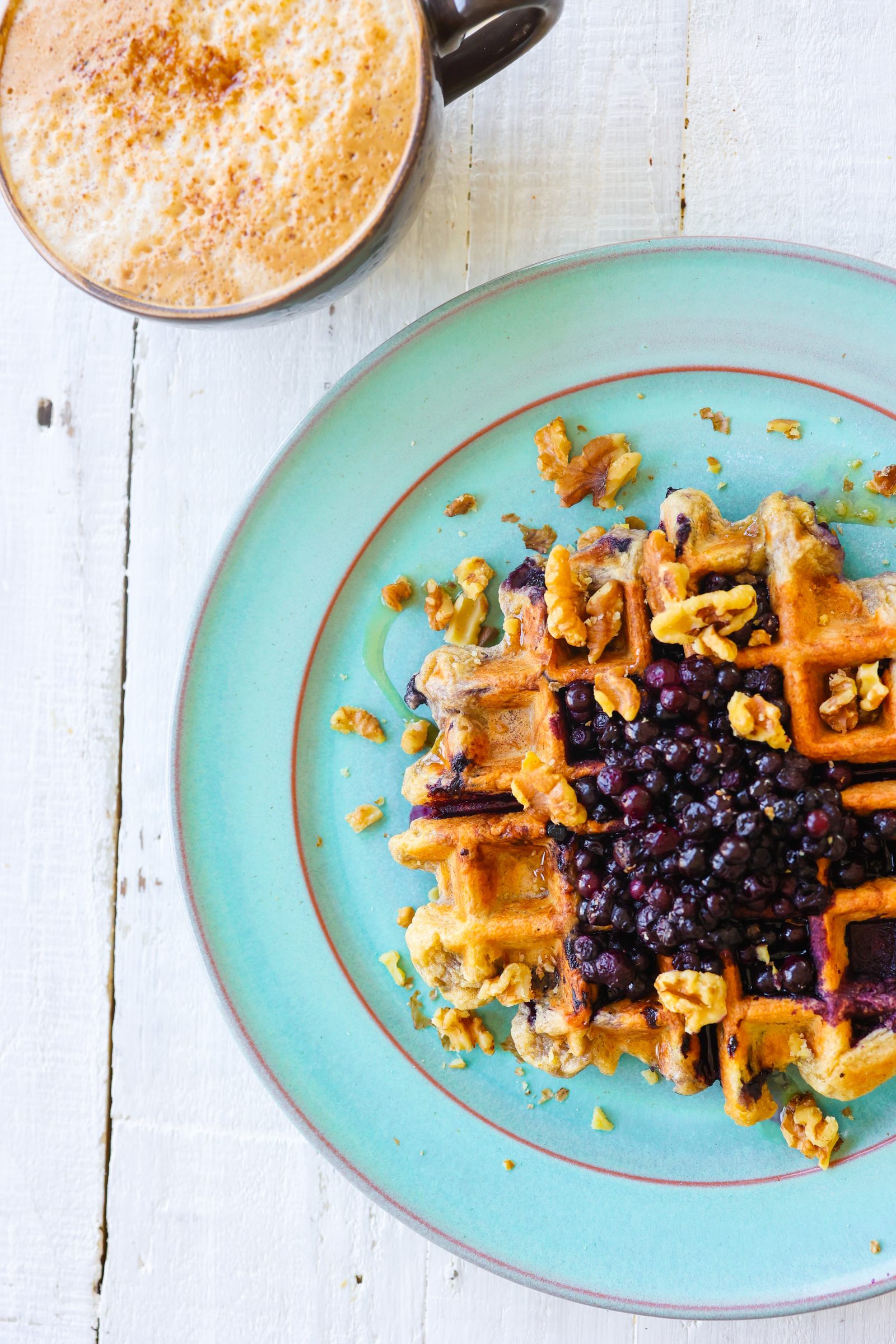 Fluffy vegan buttermilk waffles topped with blueberries and maple syrup.