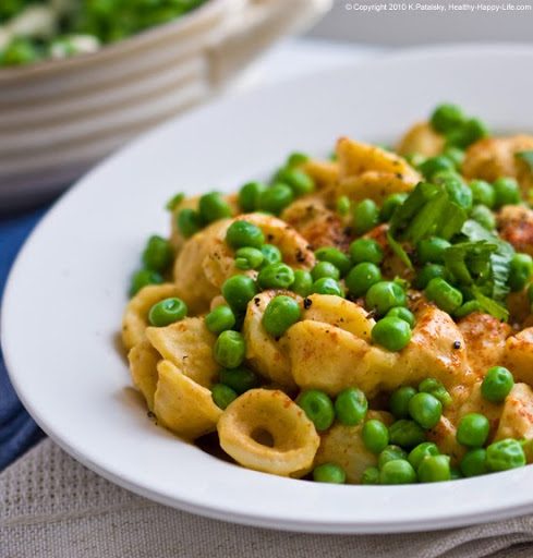 Orecchiette pasta coated in creamy vegan cheese sauce with bright green peas nestled in its little hollows.