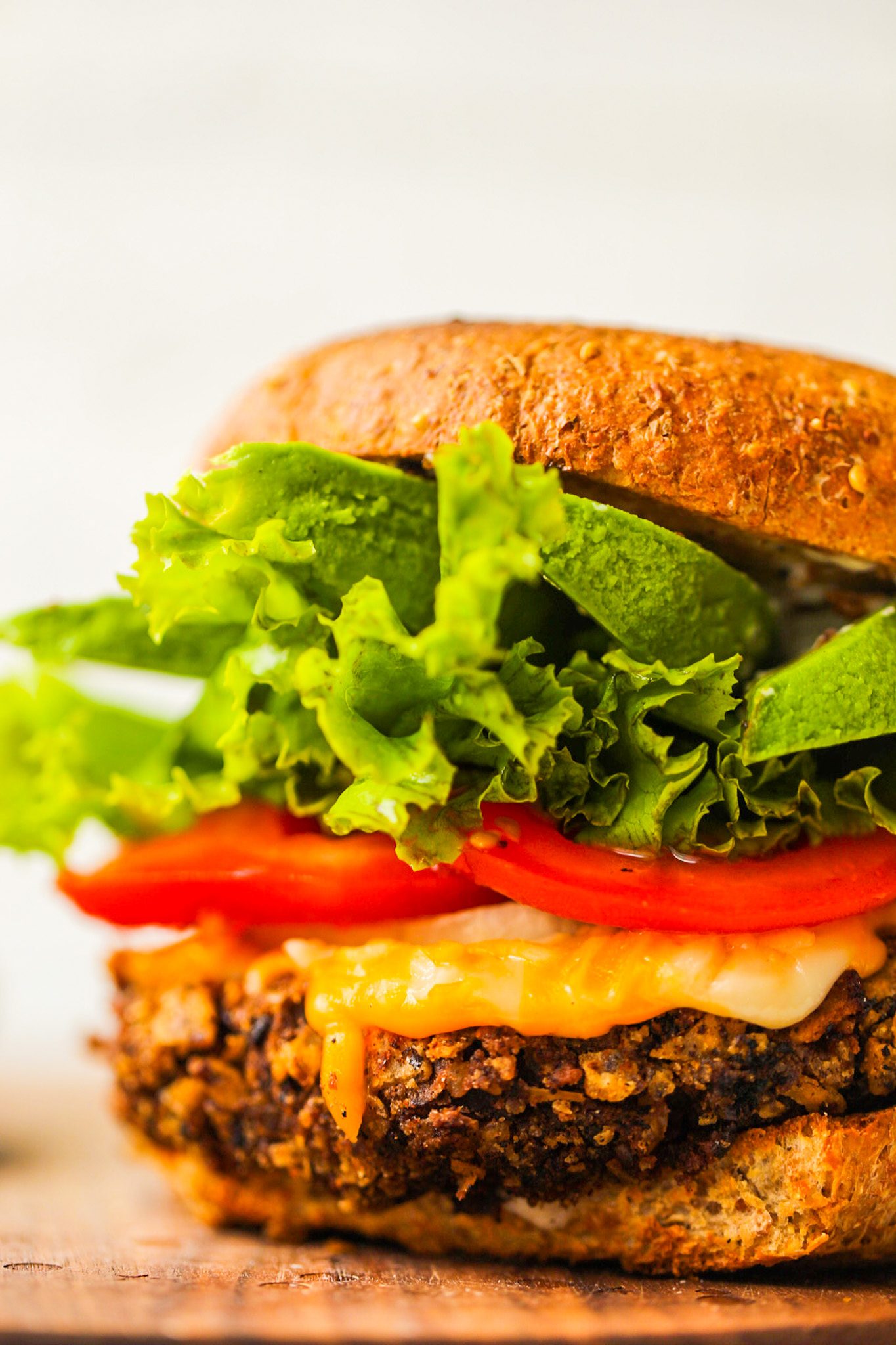 Black bean burgers topped with avocado, lettuce, tomato, onion and melted vegan cheese on toasted buns.