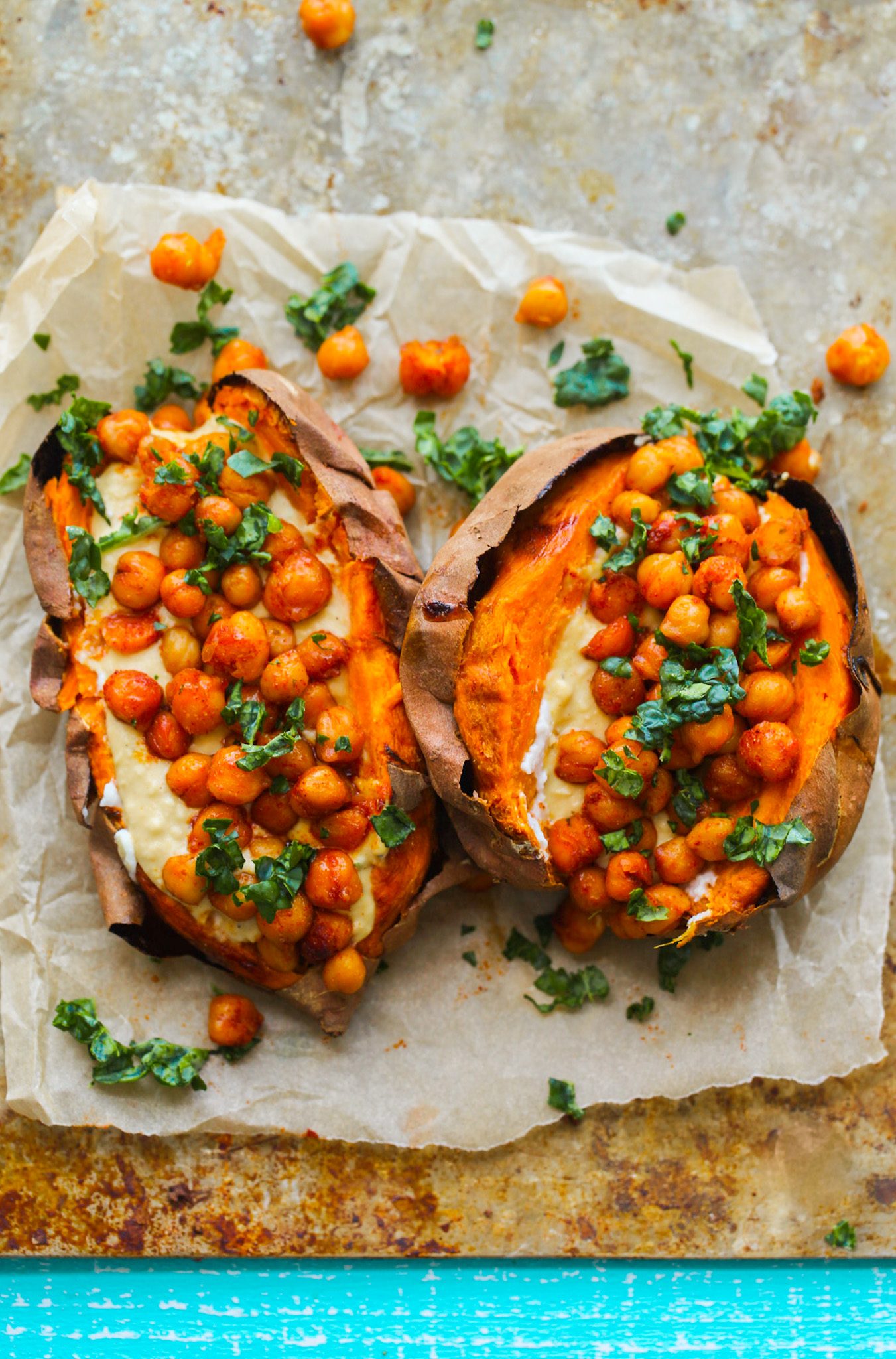 Oven-baked sweet potatoes stuffed with savory chickpeas and creamy garlic hummus.