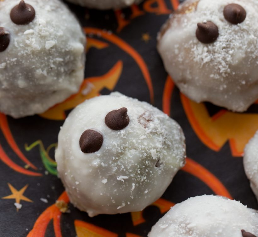 Pumpkin donut holes coated in coconut glaze with mini chocolate chip eyes to look like little ghosts.