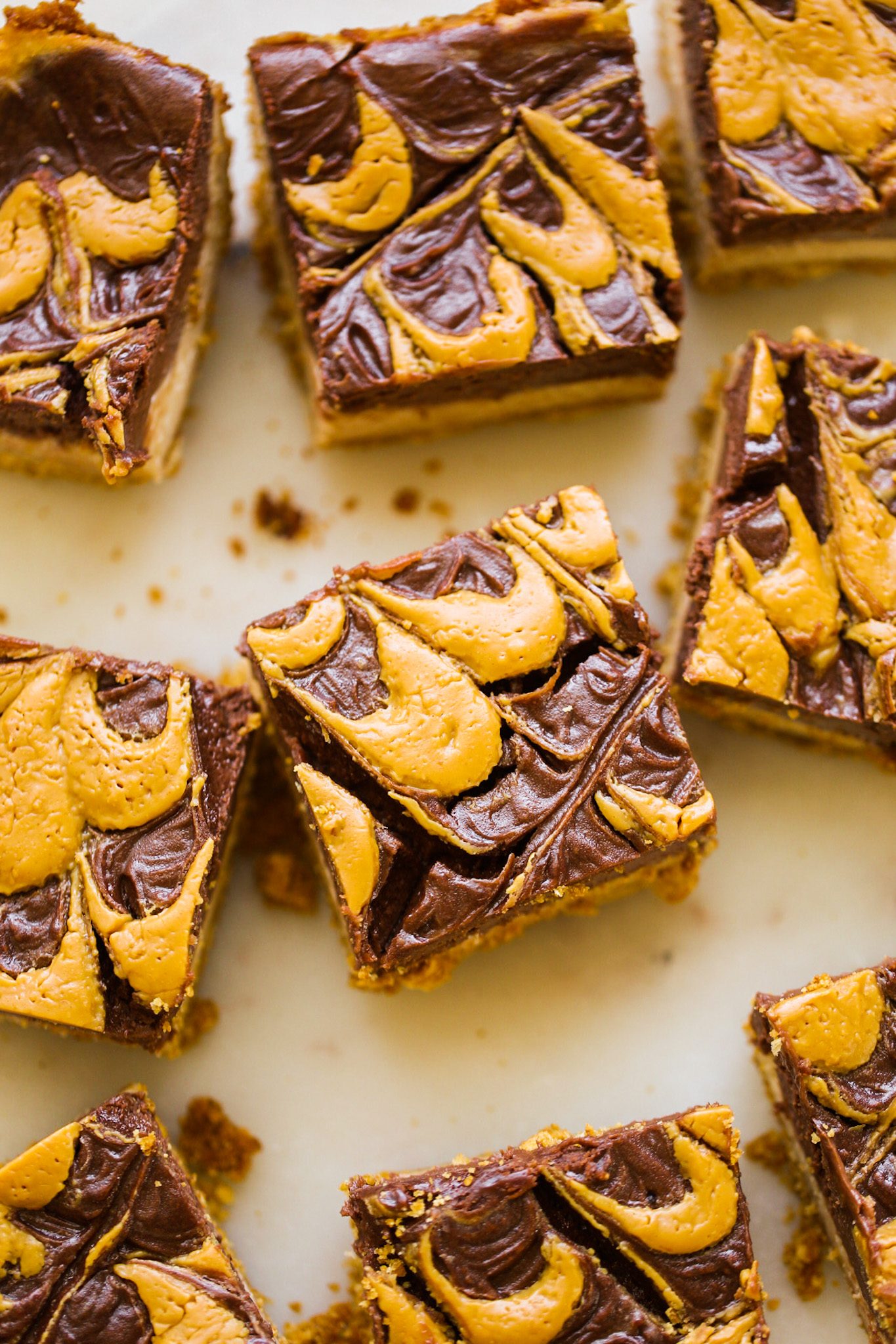 Vegan cheesecake bites with chocolate and peanut butter layers, peanut butter swirls on top, and a graham cracker crust.