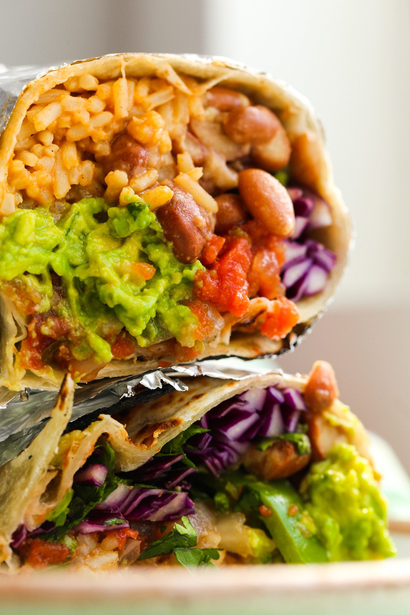 A veggie fajita burrito filled with beans, rice, sizzling vegetables, guacamole, cabbage and salsa.