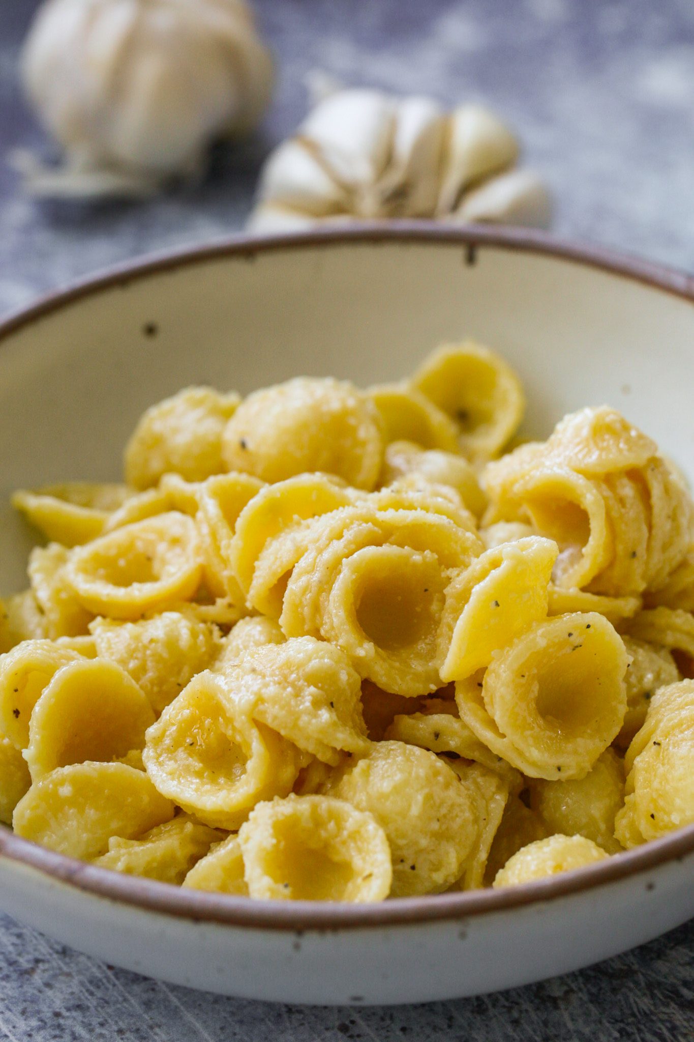 Orecchiette pasta in a creamy roasted garlic and olive oil sauce with vegan Parmesan and chopped kale.
