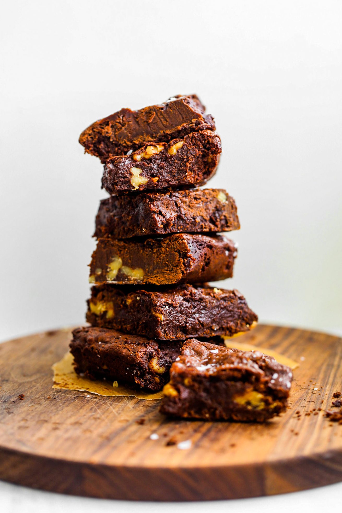 Stacked fudgy vegan chocolate brownies with shiny, crinkly tops and walnuts.