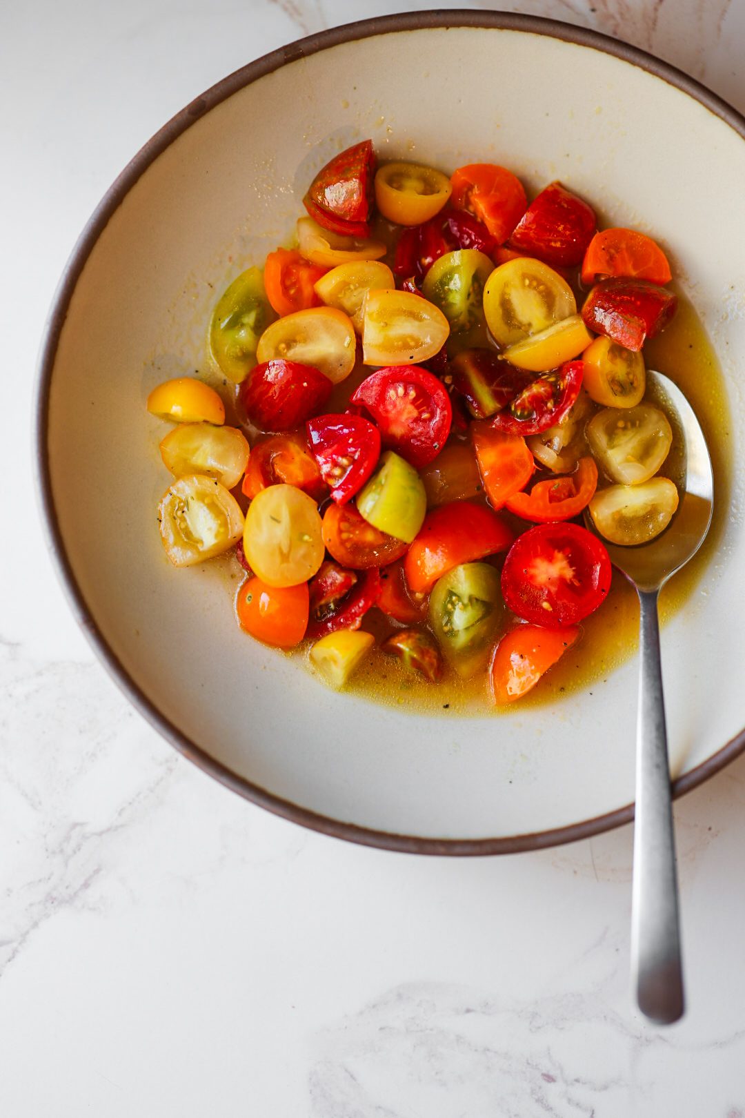 A colorful summer salad of red and yellow cherry tomatoes dressed with lemon juice and olive oil.