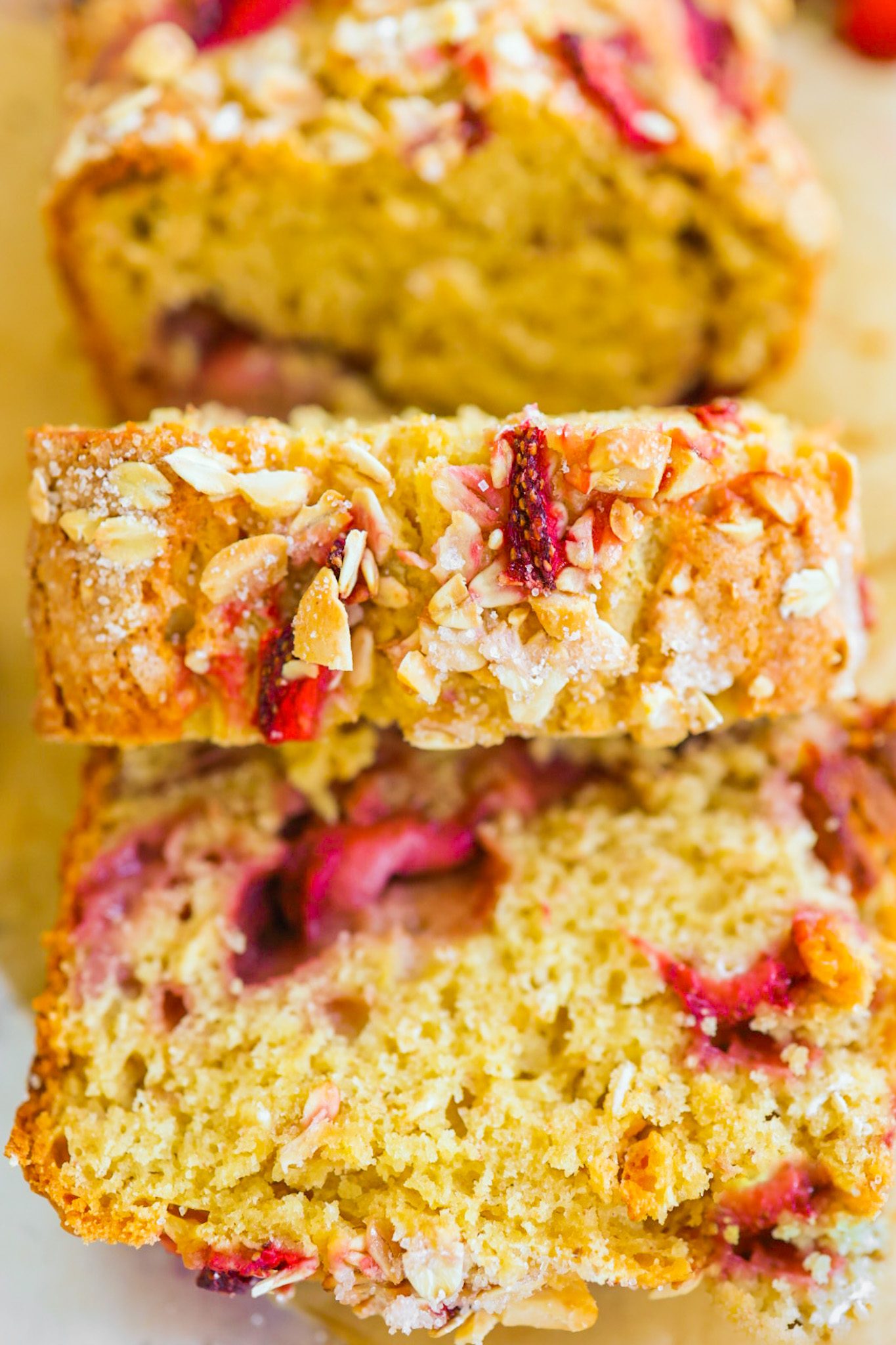 Sliced peanut butter bread studded with strawberries and topped with chopped peanuts and extra berry slices.