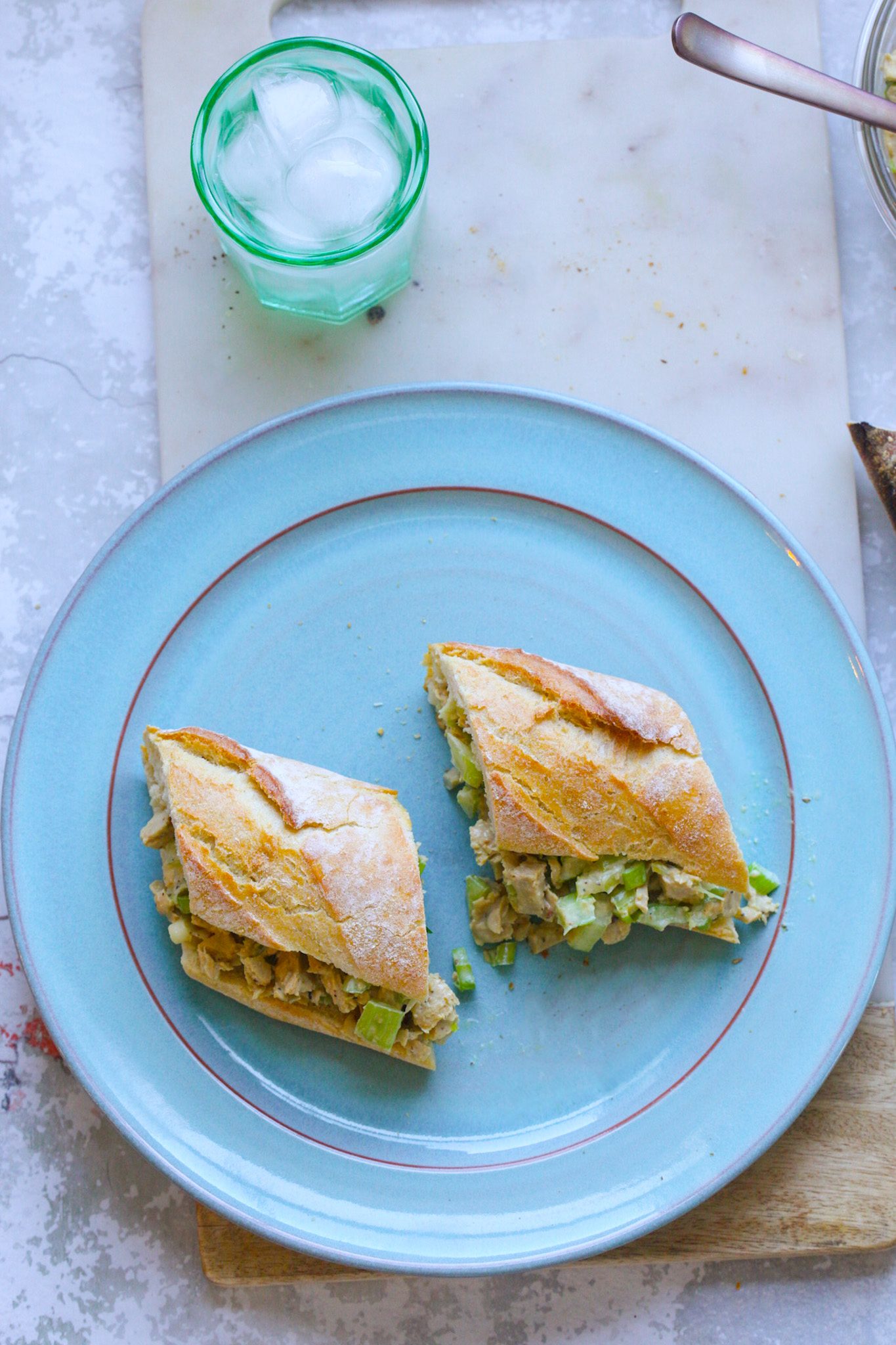Creamy vegan chick'n salad with crunchy celery served on French bread on a turquoise plate.