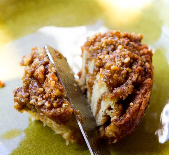 Coffee cake cinnamon rolls filled with brown sugar and walnuts, topped with orange cream frosting.